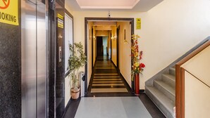 A hotel lobby with a staircase, a no-smoking sign, an elevator, and a CCTV warning sign. - Tuliip Residency (Mumbai)