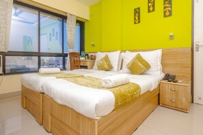 A hotel room with a large bed, a bedside table with a phone, and a window with curtains. - Tuliip Residency (Mumbai)