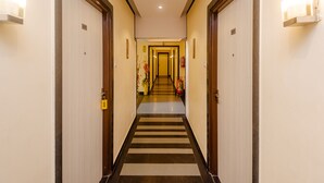 A hotel hallway with doors numbered 605 and 601, a striped carpet, and a fire extinguisher. - Tuliip Residency (Mumbai)