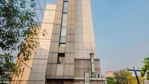 A tall, modern building with a prominent vertical window and a sign at the top. - Tuliip Residency (Mumbai)