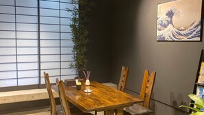 A dining area with a wooden table and chairs, a large window with a view, and a Japanese-style painting on the wall. - Bettei Shinimamiya (Osaka)