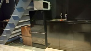 A modern kitchen with a built-in microwave, stainless steel cabinets, and a small sink. - Bettei Shinimamiya (Osaka)