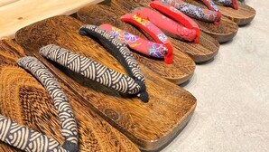 A variety of colorful slippers arranged on wooden trays. - Bettei Shinimamiya (Osaka)