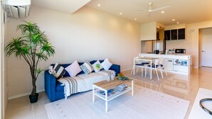 Un salon moderne avec un canapé bleu, une table basse et une plante en pot.
