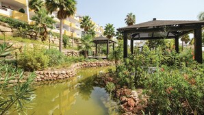 A landscaped garden with a pond, palm trees, and a gazebo.