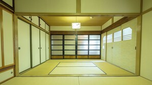 Ein traditioneller japanischer Raum mit Tatami-Bodenbelag, Schiebetüren und einer Deckenleuchte.
