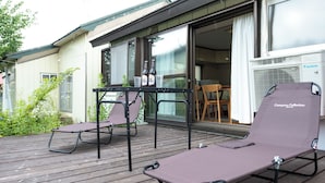 Eine Terrasse mit zwei Liegestühlen, einem Tisch mit Flaschen und einer Daikin-Klimaanlage.
