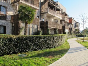 Stylish building with balconies and a beautifully manicured hedge.