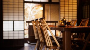 A traditional Japanese room with tatami flooring, wooden sliding doors, and a low table with chairs.