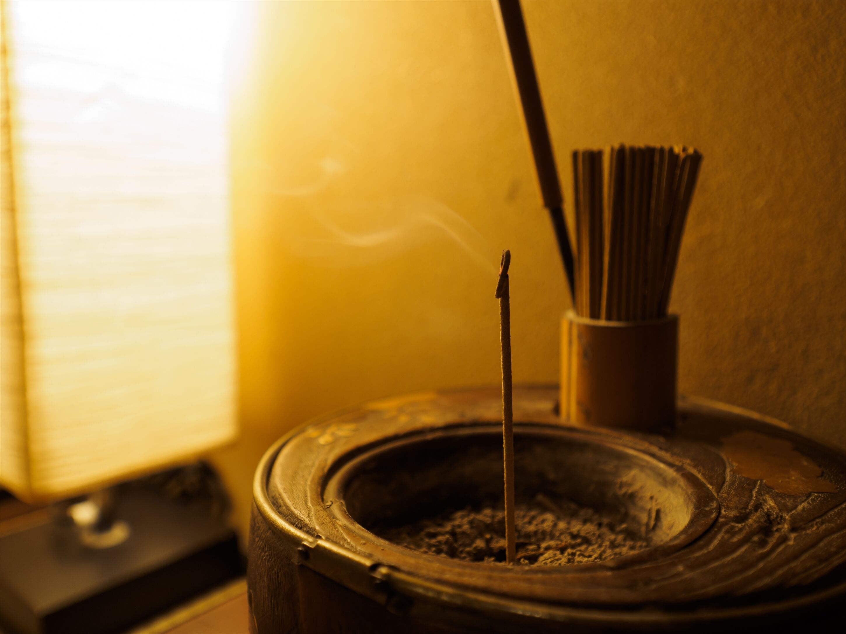Un brûle-encens traditionnel, avec un bâton d’encens à l’intérieur, posé sur une surface en bois.