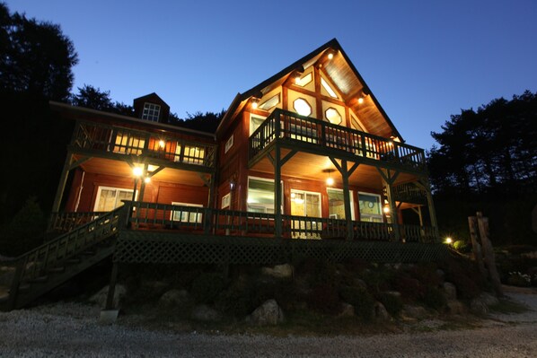 A two-story wooden house with a balcony and a staircase leading to the entrance. - Muju Naos Pension (Muju)