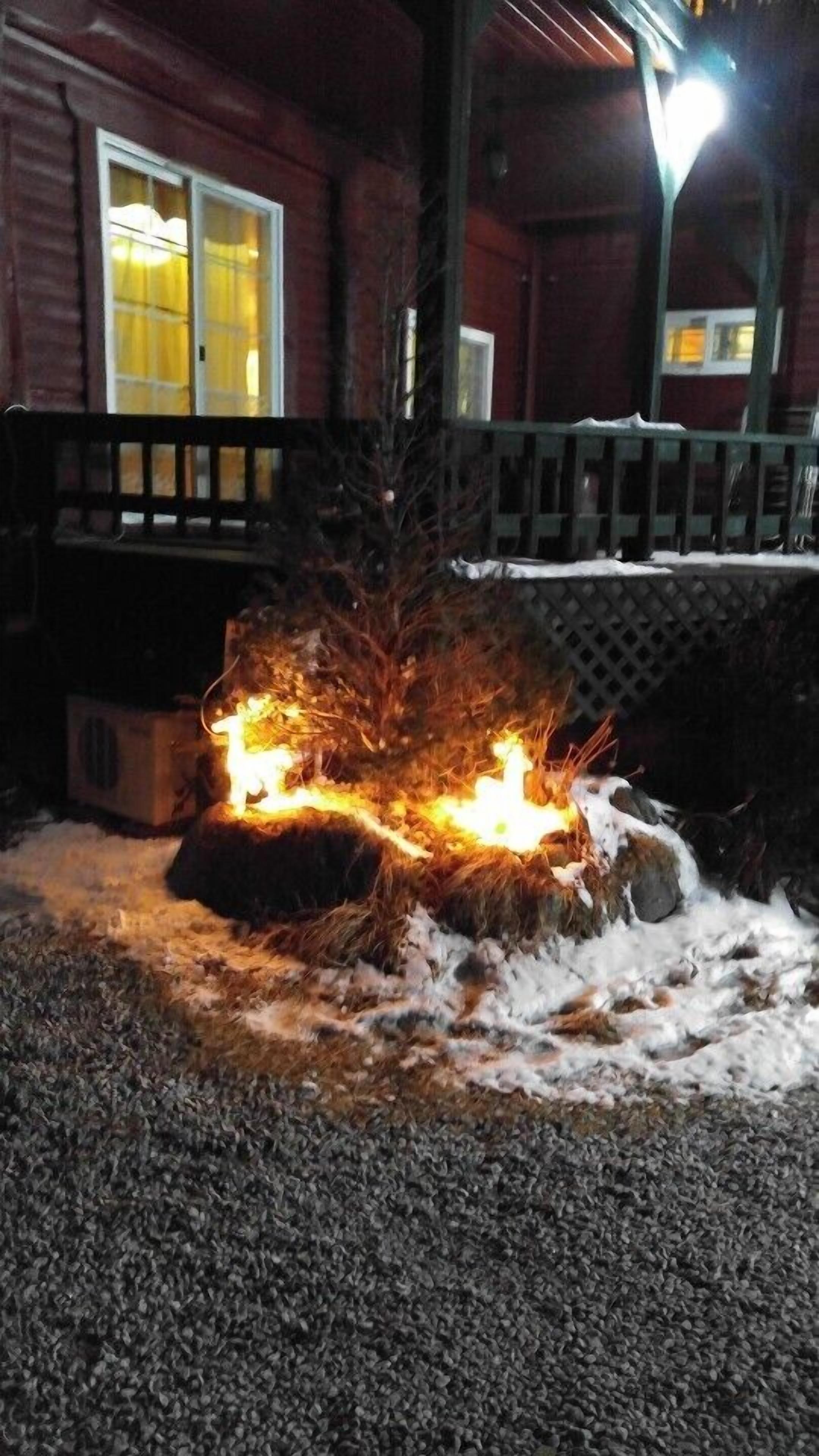 A wooden cabin with a fire burning in the snow.
