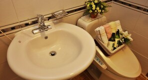A bathroom with a white sink, a toilet, and a small trash bin. - Muju Naos Pension (Muju)