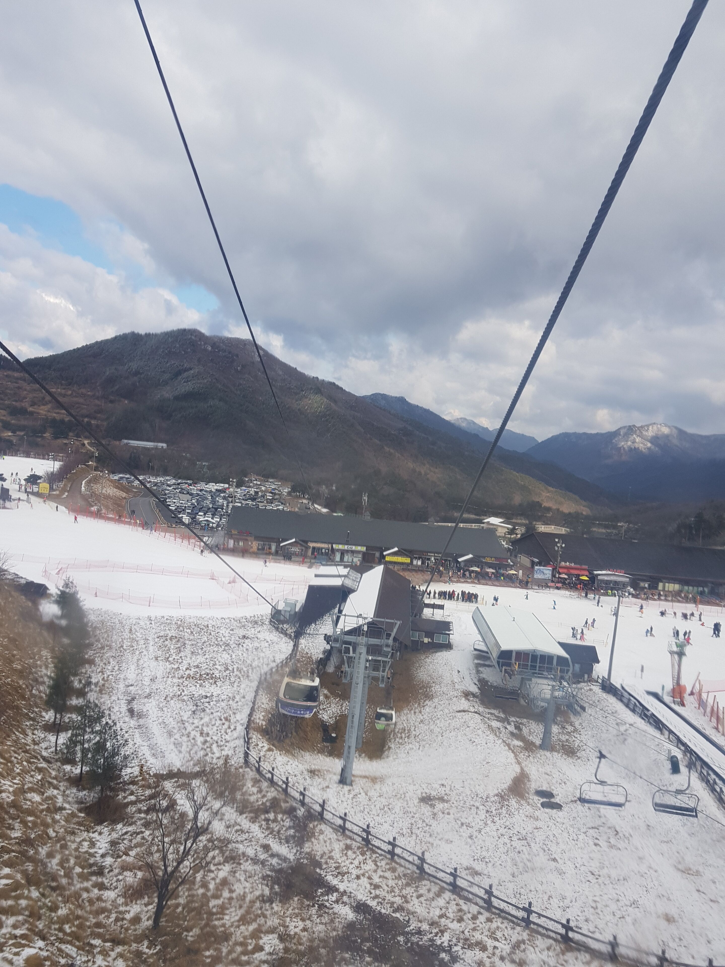 A ski resort with a chairlift, buildings, and a mountainous backdrop.