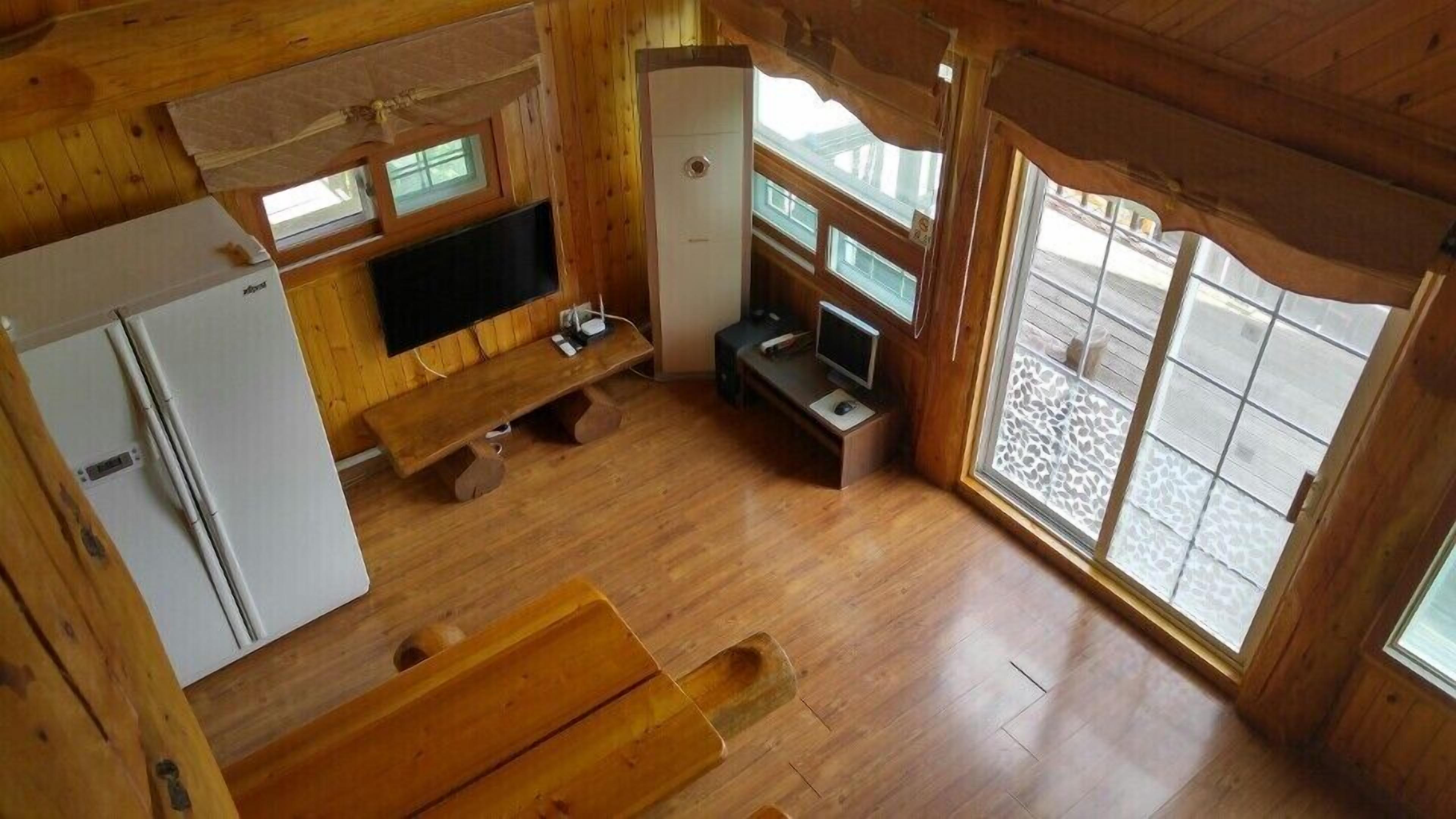 Una cabaña de madera acogedora con kitchenette, televisor de pantalla plana y una pequeña zona de estar.