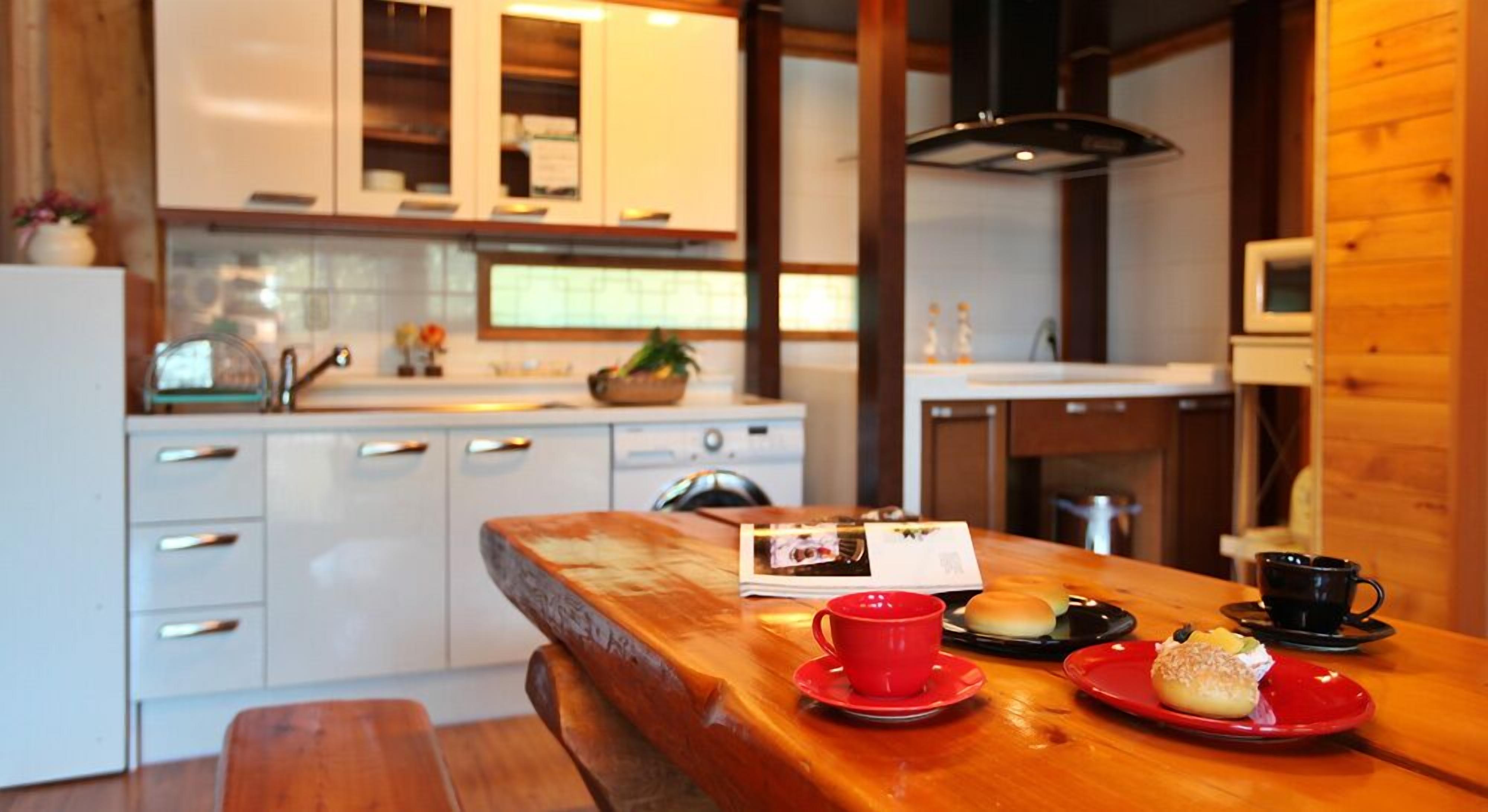 A cozy kitchen with wooden cabinets, a wooden table with a red placemat, and a bench.