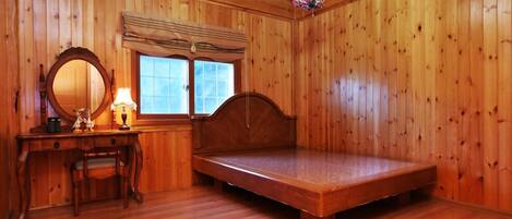 Una habitación de madera con una cama, un aparador, un espejo y una ventana.