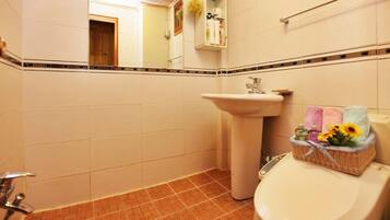 A bathroom with a white sink, a toilet, and a basket of toiletries on the toilet.