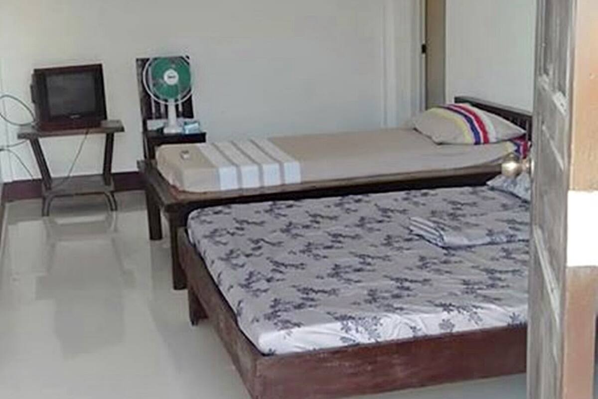 A bedroom with a bed, bedside table, and a fan.