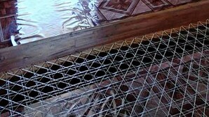 Une pièce avec un sol carrelé, une fenêtre avec des stores et une vue sur un balcon doté d’une balustrade.