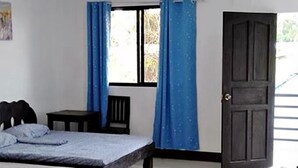 Une chambre avec deux lits, une fenêtre avec des rideaux bleus, une porte et un radiateur.