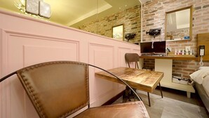 A hotel room with a brick wall, a wooden table, a leather chair, a bed, and a small kitchenette. - February Hotel Busan Gangseo Annex Building  (Busan)
