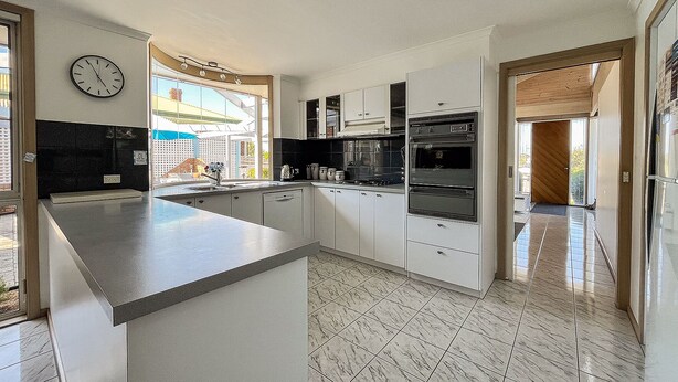 Een moderne keuken met een groot eiland, inbouwapparatuur en uitzicht door het raam.