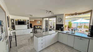 Een moderne keuken met witte kastjes, een centraal eiland en een eethoek.