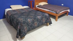 Een kamer met twee houten bedden, waarvan één een bedlaken met een patroon heeft en de ander een strepenkleed.