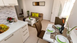 Et moderne køkken med spiseplads, en sofa og et spisebord dækket til to personer.