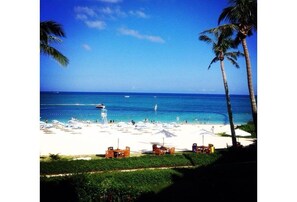 A beach with palm trees, a lifeguard tower, and umbrellas. - K Seaveiw 250㎡ ONNA 2 big suites, 3 full bath 3F (Nakadomari, Onna, Kunigami-gun)