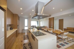 A modern kitchen with a central island, built-in appliances, and a dining area with a wooden table and chairs.