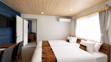 Quarto de hotel com cama, escrivaninha, cadeira e televisão.