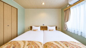 A double bed with a floral bedspread, a wooden headboard, and a window with curtains. - Stay SAKURA Kyoto Kiyomizu Ougi (Kyoto)