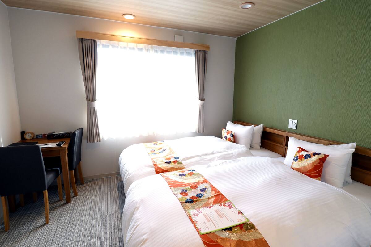 Een hotelkamer met twee bedden, een bureau en een stoel.