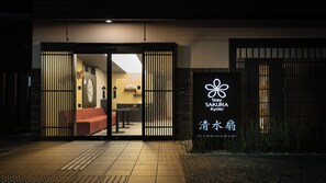 Entrada d'hotel amb una porta corredissa, una taula de recepció i un cartell amb el nom de l'hotel.