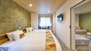 Habitació d'hotel amb un llit gran, una televisió penjada a la paret i una zona de seients separada amb un sofà i cadires.