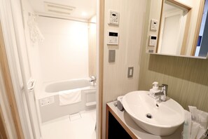 Un baño moderno con bañera, lavamanos y espejo.