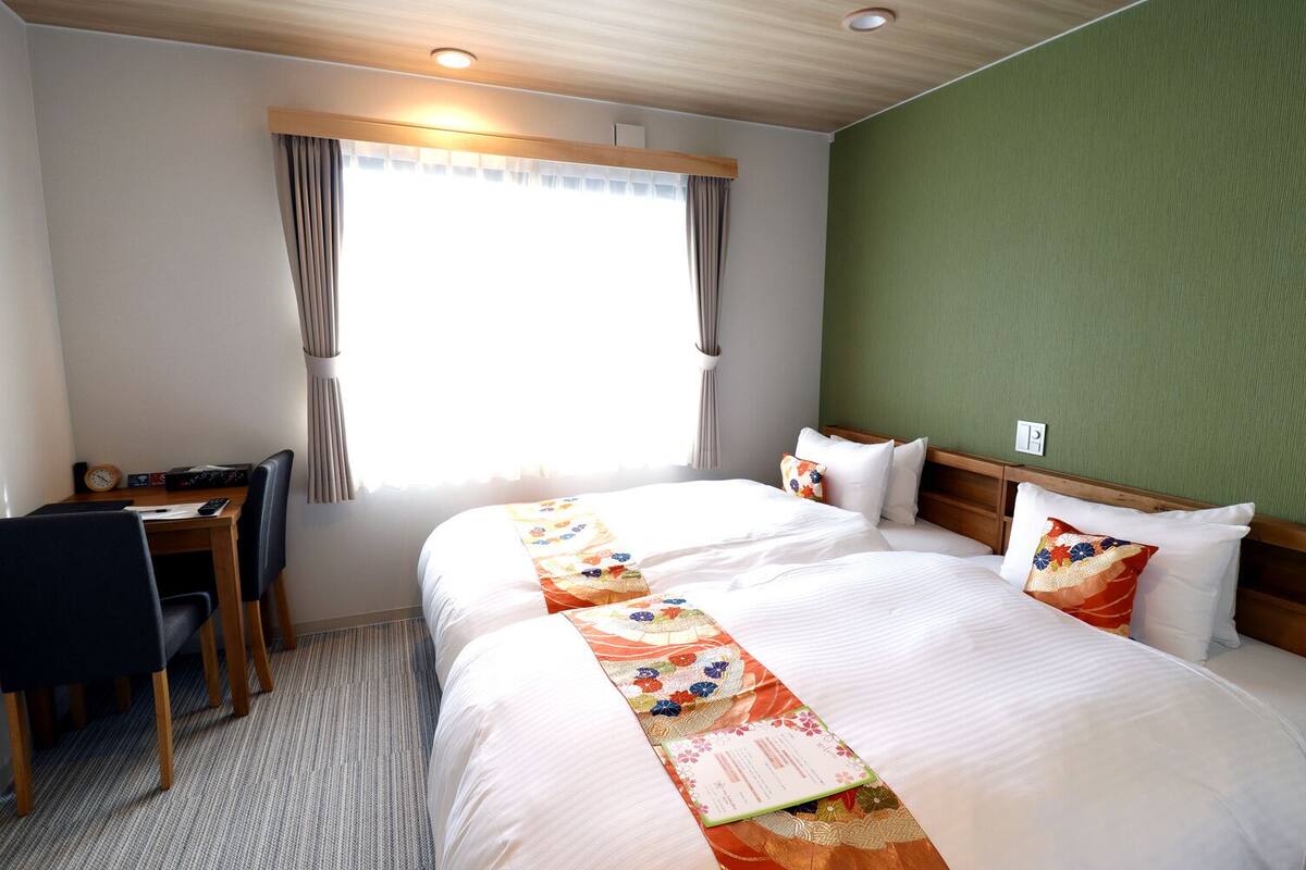 Een hotelkamer met twee bedden, een bureau en een stoel.