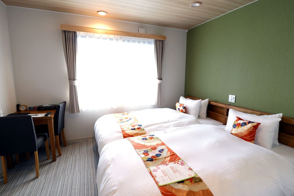 Une chambre d’hôtel avec deux lits, un bureau et une chaise.