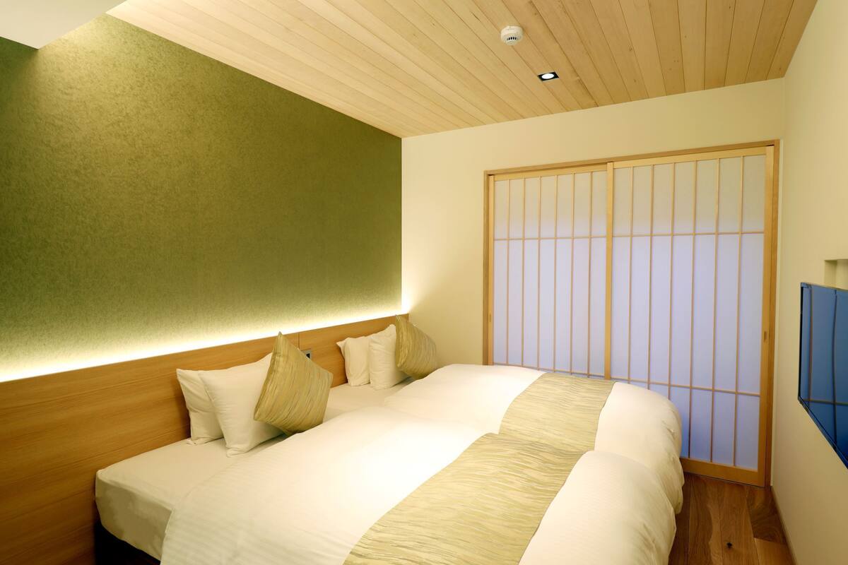 A hotel room with a bed, wooden headboard, and a shoji screen.