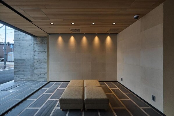 Un interior moderno con un banco, iluminación empotrada y una pared de concreto.
