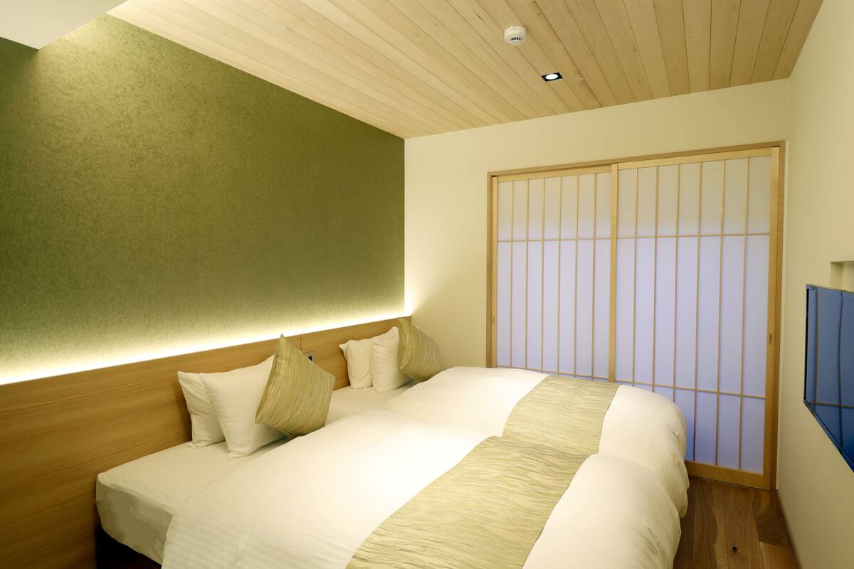 A hotel room with a bed, wooden headboard, and a shoji screen.
