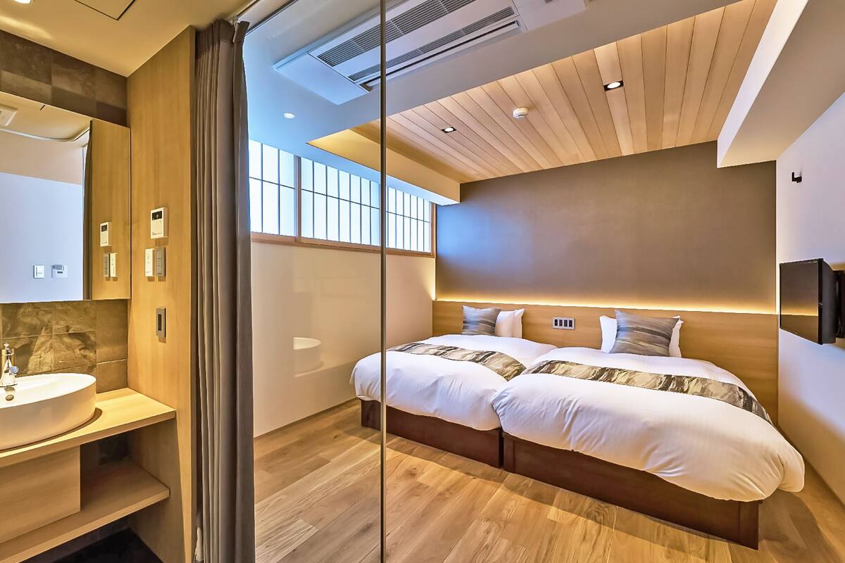 A modern hotel room with a large bed, a bathroom with a sink, and a view of the city.