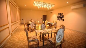 A dining area with a chandelier, floral-patterned chairs, and a table. - Solitaire Resort (Udaipur)