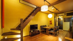 Un coin repas avec une table et des chaises en bois, un escalier et un téléviseur.