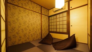 Une pièce de style japonais traditionnel, avec un sol recouvert de tatamis, des paravents en papier de riz (shoji) et un futon avec des coussins.