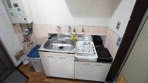A compact kitchen with a sink, stove, and storage cabinets. - Apartment BS Kawara Heights Namba (Osaka)