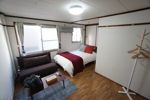 Una habitación funcional con cama, sofá, una mesita y un armario.