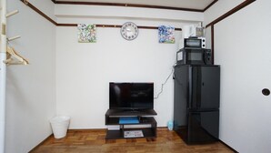 A small living room with a flat-screen TV, a refrigerator, and a clock on the wall. - Apartment BS Kawara Heights Namba (Osaka)